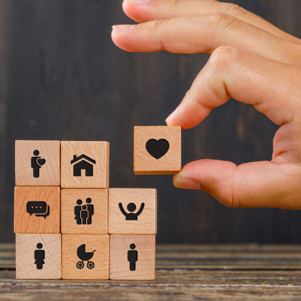 Relationship concept on wooden background side view. hand holding wooden cube with heart icon.